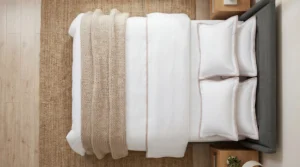 Hotel-quality bed setup with white cotton sheets and layered bedding in a modern bedroom